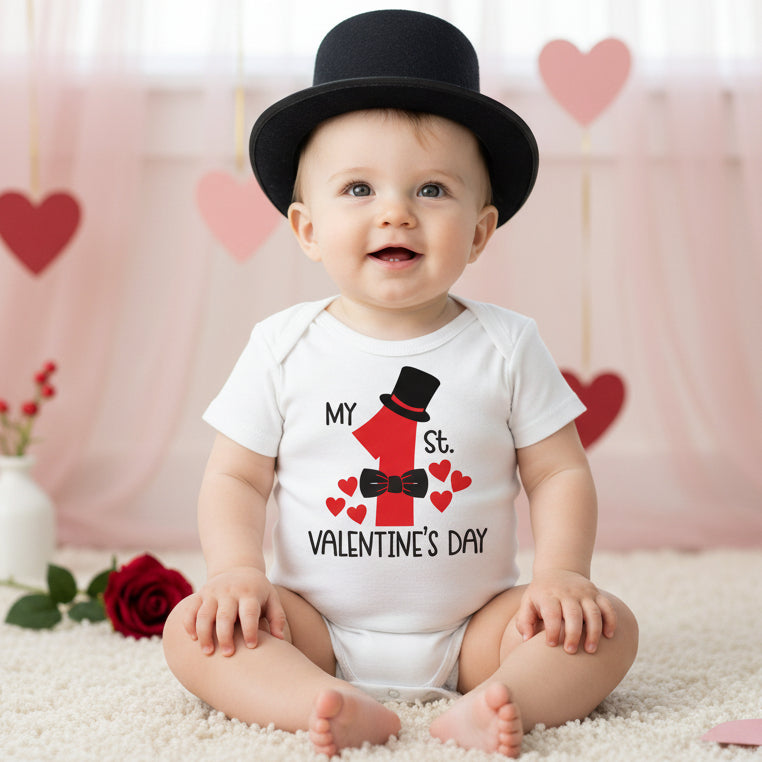 White baby bodysuit with a design that includes a top hat, bow tie, and hearts, along with the text 'MY 1ST VALENTINE'S DAY'.